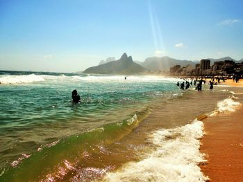 People enjoying at beach against clear sky