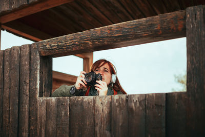 Portrait of woman photographing through fence