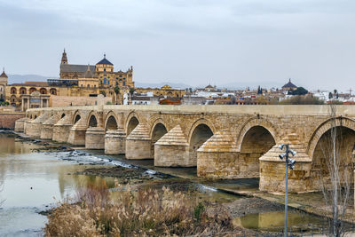 Arch bridge over river against sky