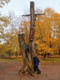 Woman standing by tree trunk during autumn