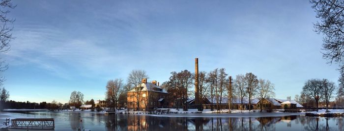 Reflection of bare trees in lake against sky