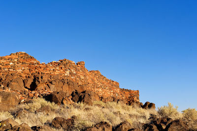 Low angle view of rocks against clear blue sky