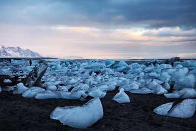 Snow covered landscape against sky during sunset