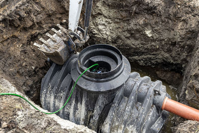 Installation of a single-chamber home sewage treatment plant, the excavator raises the tank.