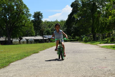 Full length portrait of woman riding bicycle on road