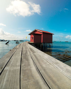 House on pier by sea against sky