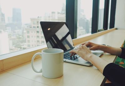 Low section of person holding coffee cup on table