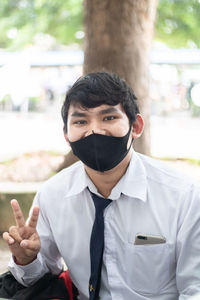 Portrait of young man wearing mask sitting outdoors