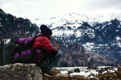 Rear view of man standing on snowcapped mountain