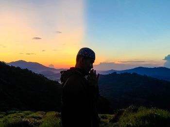 Man standing on mountain against sky during sunset