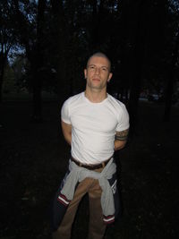 Portrait of young man standing against trees