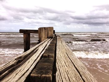 Wooden pier on beach against sky