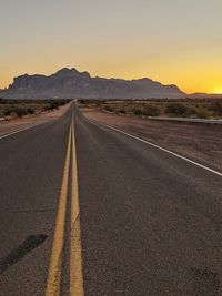 Empty road along landscape at sunrise