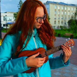 Close-up of young woman playing ukelele at park