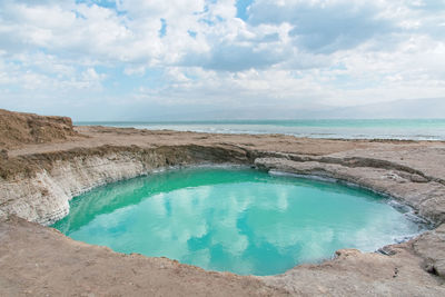 Sinkhole filled with turquoise water, near dead sea coastline. hole formed when underground salt is