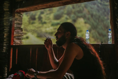 Side view of young man smoking outdoors