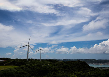 Low angle view of windmills against sky