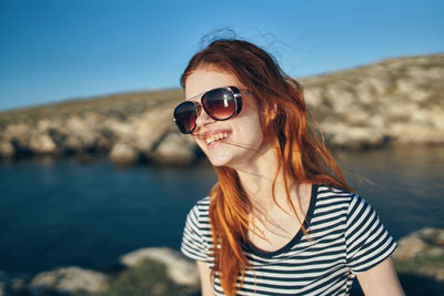 Portrait of young woman wearing sunglasses against sea