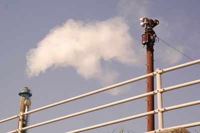 Low angle view of smoke stacks against sky