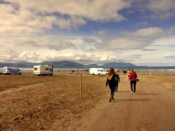 People on beach against cloudy sky