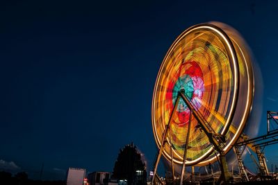 Low angle view of illuminated ferris wheel against clear sky at night