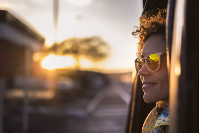 Smiling woman wearing sunglasses while traveling in vehicle