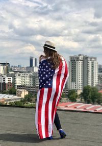 Rear view of woman with american flag on terrace against city