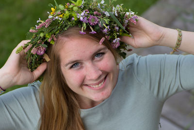 Portrait of a smiling young woman against blue flowering plants