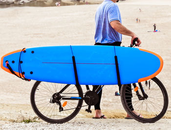 Side view of man with bicycle and surfboard