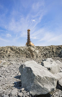 Cross on rock by building against sky