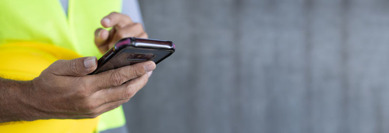 Midsection of man using mobile phone against wall