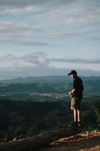 Rear view of woman standing on mountain against sky during sunset