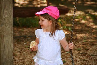 Happy girl holding bread and chain in park