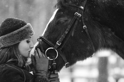 Close-up of beautiful woman with horse on field during snowfall