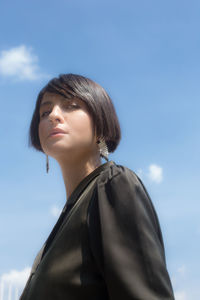 Low angle portrait of woman standing against sky