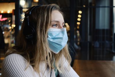 Close-up of woman wearing mask sitting at cafe