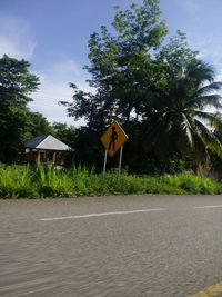 Road by trees against sky