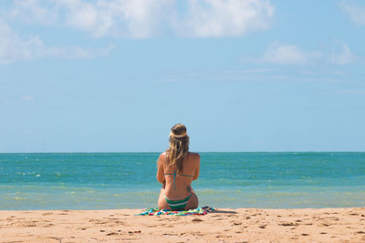 Rear view of woman at beach against sky