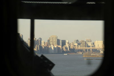 Buildings by city against sky seen through window