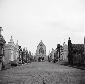 Street amidst cemetery by church against sky