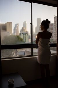 Rear view of woman looking through window