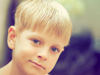 Close-up portrait of boy with blond hair on sunny day