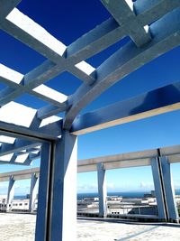 Low angle view of bridge over sea against clear blue sky