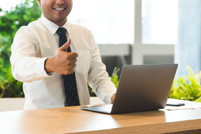 Midsection of man using laptop on table