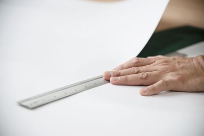 Close-up of hand holding paper against white background