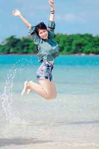 Full length of a young woman jumping in water