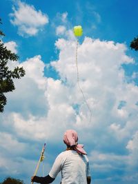 Low angle view of people against cloudy sky