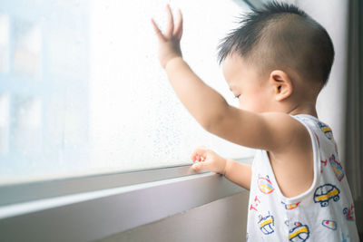 Smiling cute boy sitting by window at home