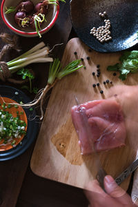 Digital composite image of hands cutting pork on board