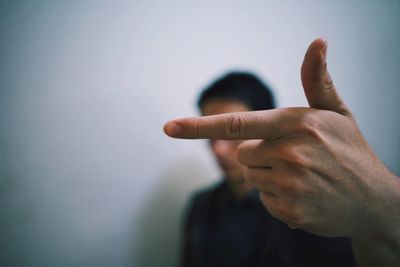 Close-up of man gesturing against wall